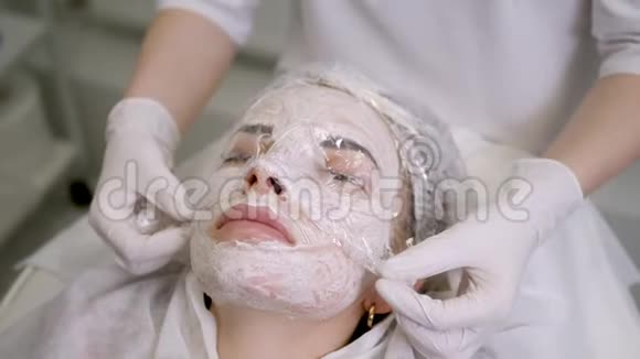 医生美容师从女孩身上取下一张透明的胶卷视频的预览图