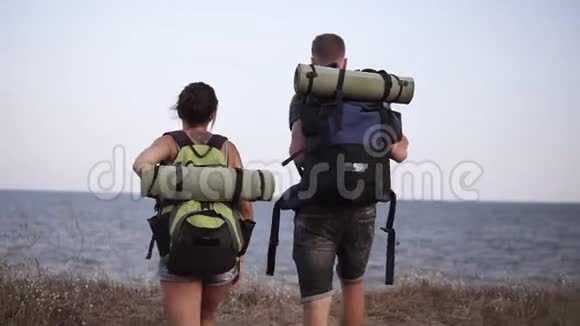 年轻的徒步情侣在山上休息年轻女子和男子徒步旅行者脱下背包坐在地上享受着视频的预览图