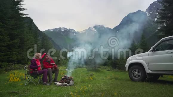 一对夫妇在一个黑暗的山谷里的露营中篝火聊天白色的车视频的预览图