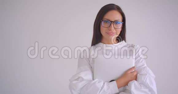 一位年轻漂亮的白种人女商人戴着眼镜手持笔记本电脑看着站在镜头前的镜头视频的预览图