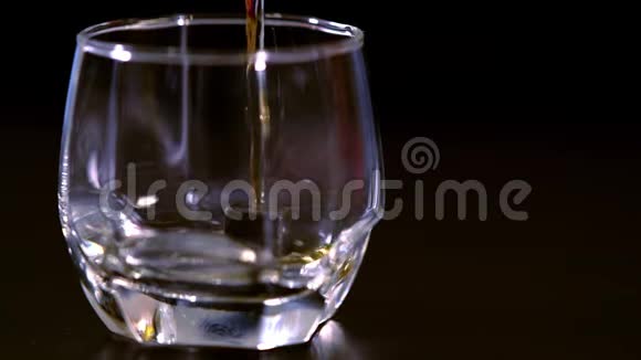 将白兰地或威士忌倒入加冰的玻璃杯中视频的预览图