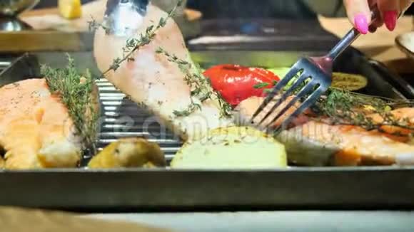 烤鱼烤三文鱼牛排鸡肉芳香香料和烤蔬菜牛排用叉子翻转靠近视频的预览图