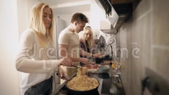 侧面看朋友一起在厨房做饭晚上吃美味的食物视频的预览图