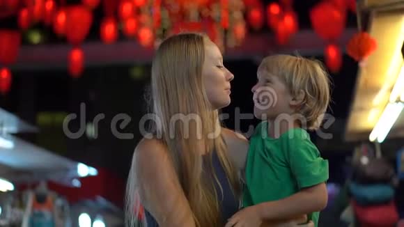 一位年轻女子和她的小儿子在一条街上玩得很开心街上有许多红色的中国红灯笼视频的预览图