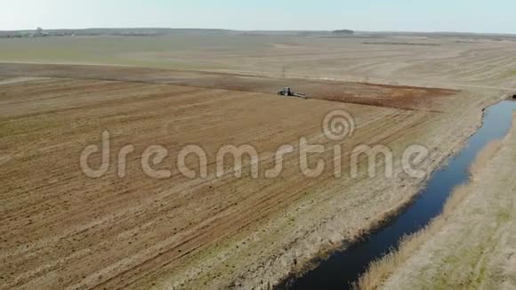 带犁的蓝色拖拉机在一条干净的小河附近播种下的土壤视频的预览图
