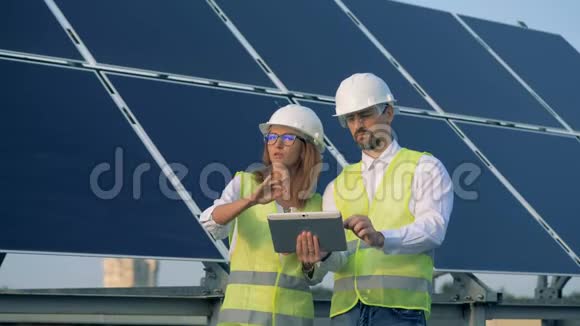 建筑工人在讨论和规划过程中同时站在太阳能电池板旁边视频的预览图
