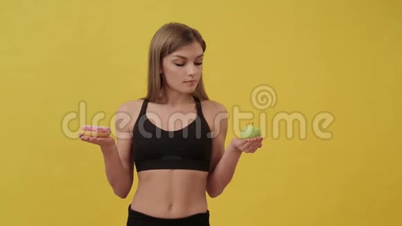 节食的运动女孩在甜甜圈和苹果之间选择健康生活方式视频的预览图