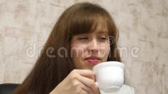 女商人坐在办公室的椅子上说着喝着白杯子里的咖啡笑着年轻女性视频的预览图