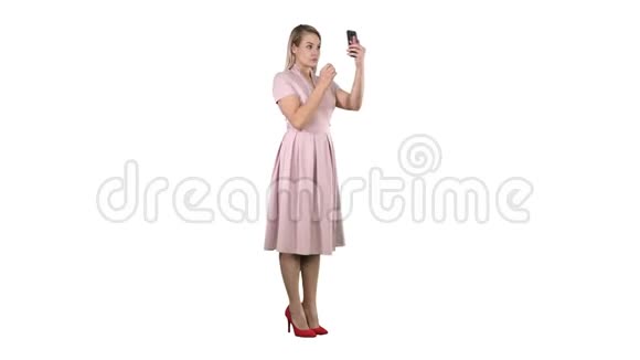 美女看着自己在她的智能手机固定她的头发白色背景视频的预览图