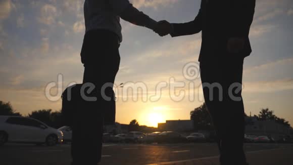 日落时分两位商人在城市环境中互相问候户外商务握手男性手臂晃动视频的预览图