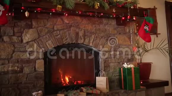戴着针织毛衣戴着圣诞花环挂着五颜六色闪光花环的壁炉上方的笑容满面的胡子男人视频的预览图