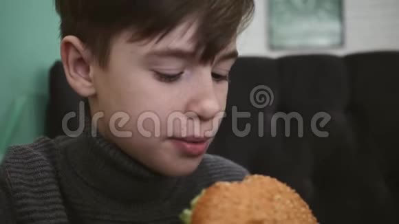 在餐馆吃汉堡的男孩这个男孩拿着一个牛肉汉堡视频的预览图