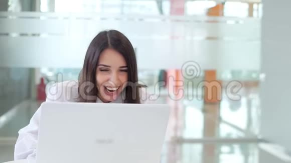 办公室里上班的女孩看着笔记本电脑笑了起来慢动作视频的预览图