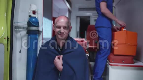 坐在救护车里的人坐在毯子里微笑视频的预览图