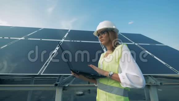 女建筑工人正带着电脑沿着太阳能电池板行走视频的预览图