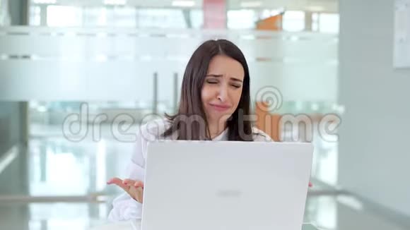 桌子旁工作的女孩很情绪化因为笔记本电脑坏了视频的预览图