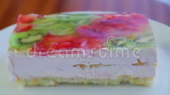 水果蛋糕上有猕猴桃和草莓果冻放在白色盘子里旋转成一圈视频的预览图