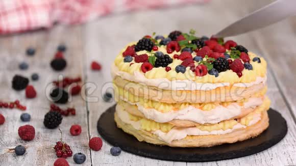 用浆果和薄荷装饰在桌子上的分层蛋糕女人切美味的泡芙糕点蛋糕视频的预览图