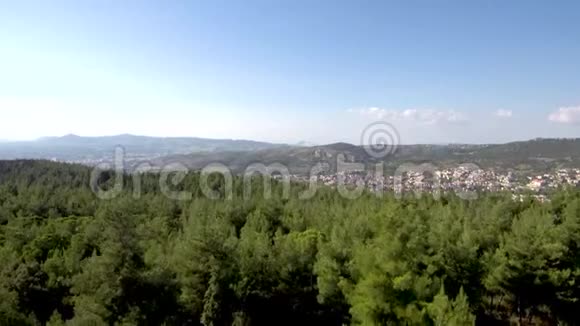 在希腊塞萨洛尼基阿斯维托霍里地区和一个村庄旁边的空中森林景观由无人机向上移动视频的预览图