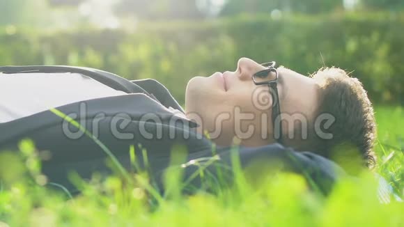 穿着正式服装的男性躺在草地上享受阳光摆脱压力视频的预览图