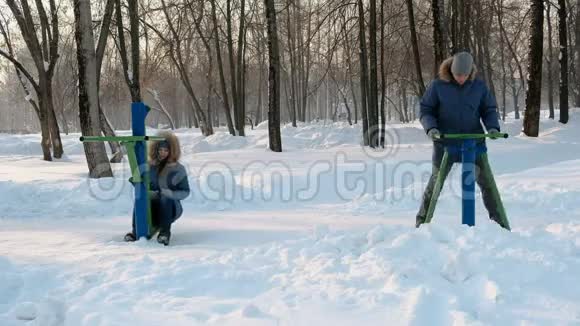 穿着蓝色夹克的男人和女人在冬季公园里从事模拟器和谈话前景视频的预览图