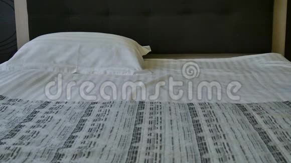 酒店客房的准备工作在酒店房间或豪华的家中为刚铺好的床抚平枕头酒店视频的预览图