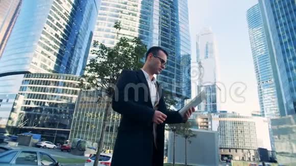 由摩天大楼组成的商业综合体旁边站着一位年轻成功的男性商人视频的预览图