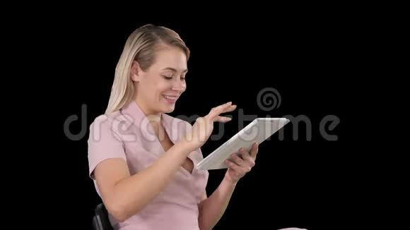 坐着看平板电脑的女人微笑着阿尔法频道视频的预览图