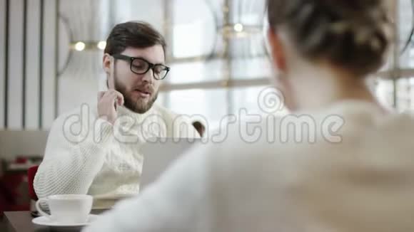 成年男子在咖啡馆的桌旁用笔记本电脑与妻子交谈视频的预览图