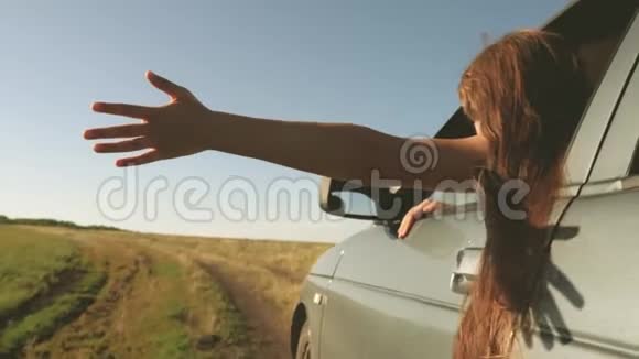 快乐的女性旅行者沿着乡间小路开车车窗上的手抓住了风长发女孩视频的预览图