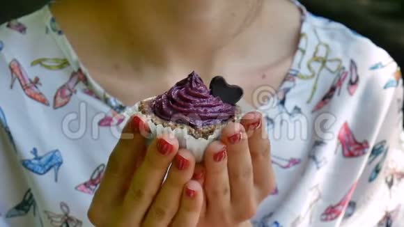 女性手拿着紫罗兰小杯蛋糕外门装饰着巧克力小心脏食物和糖果美味佳肴视频的预览图