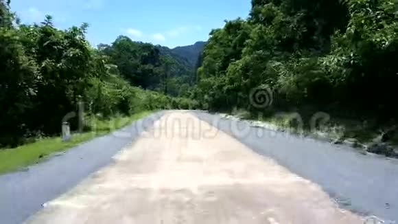 热带公路穿过树木穿过形状奇特的山丘视频的预览图