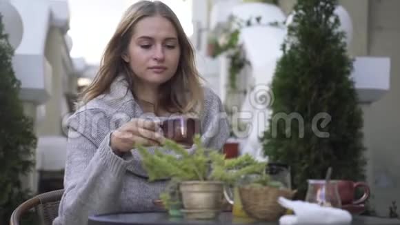 漂亮的女孩在咖啡馆的露台上喝咖啡视频的预览图