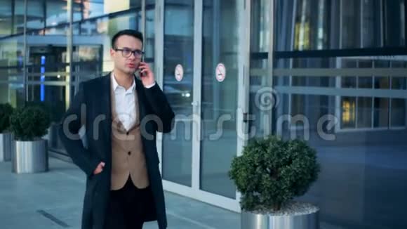 商人正走在一栋大楼附近用他的电话交谈红色史诗影院镜头拍摄视频的预览图