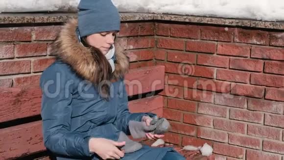 女人很冷她戴上手套坐在长凳上背景砖墙视频的预览图