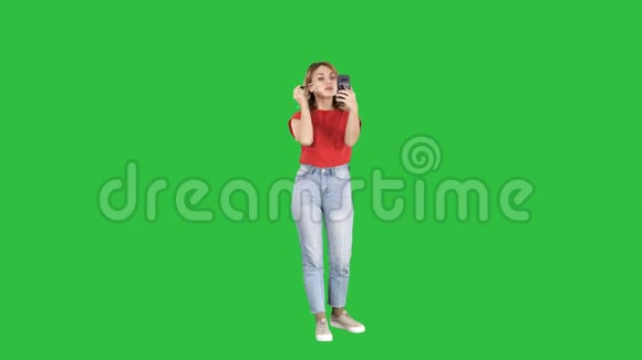 美丽的年轻女子使用睫毛膏并在她的智能手机上的绿色屏幕铬键视频的预览图
