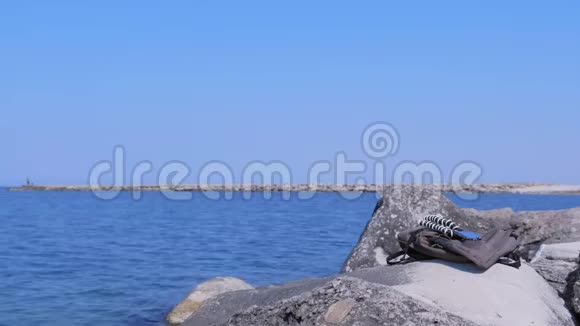 背包和智能手机在三脚架上的巨大石头在海边视频的预览图