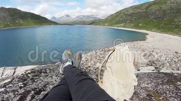 孤独的旅行者坐在挪威峡湾上方的岩石上视频的预览图
