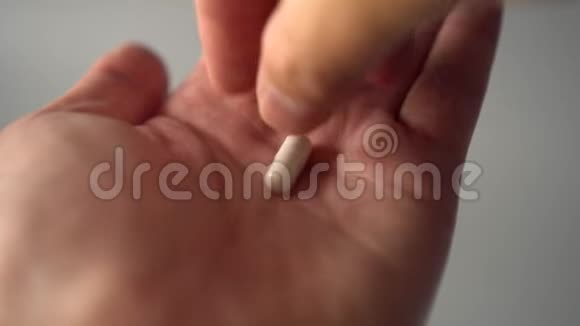 一只手从手掌上取出一个医用白色胶囊视频的预览图
