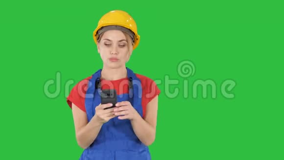 年轻的职业女性承包商戴着硬帽子用手机在绿色屏幕上发短信铬键视频的预览图