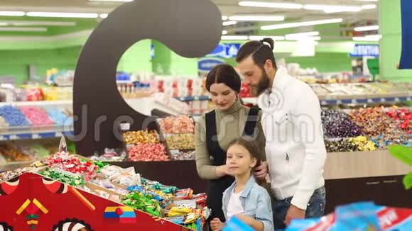 有个小女儿的年轻父母在超市里选择甜巧克力视频的预览图