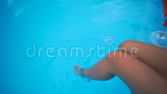 女腿在游泳池里飞溅在阳光明媚的夏日里小女孩双腿在清澈的池水里呀视频的预览图