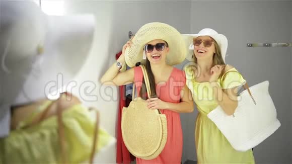 两个女人在镜子附近买有趣的衣服试衣间漂亮的年轻购物者视频的预览图