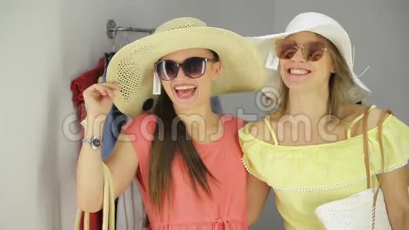 两个女人在镜子附近买有趣的衣服试衣间漂亮的年轻购物者视频的预览图