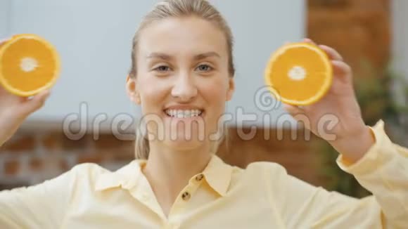年轻的女人拿着橘子片靠近她的眼睛微笑视频的预览图