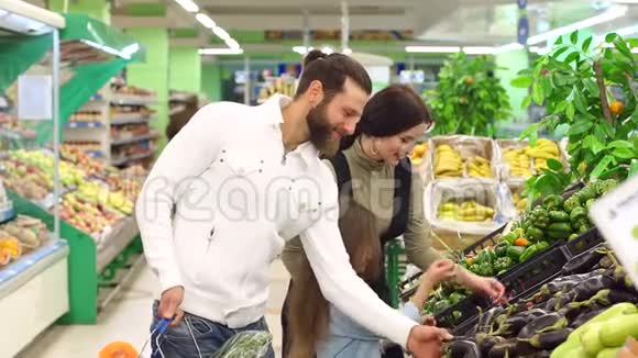 一个年轻的家庭有一个可爱的女儿在超市买蔬菜慢点视频的预览图