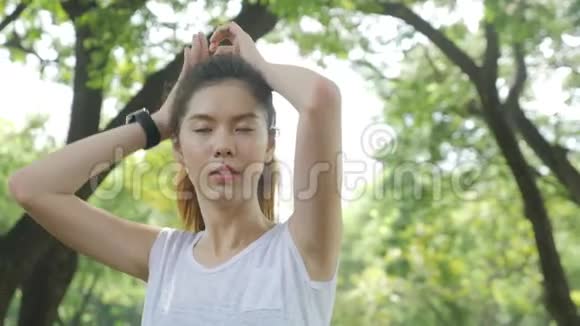 在城市公园晨跑之前运动的年轻亚洲女人把头发剪直视频的预览图