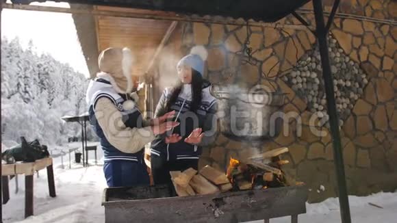 在一个晴朗的冬天两个女朋友准备在一个木屋的院子里明火视频的预览图
