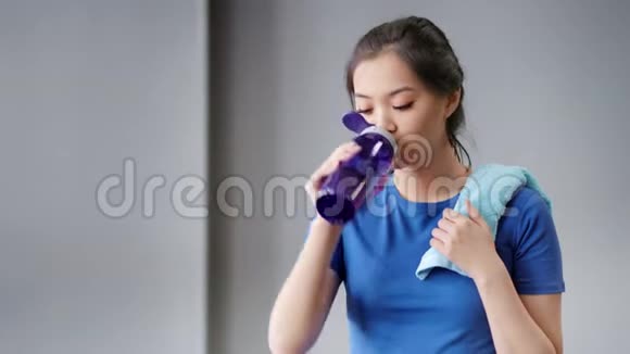 中度特写照片微笑的亚洲妇女锻炼后疲惫从瓶子里喝水视频的预览图