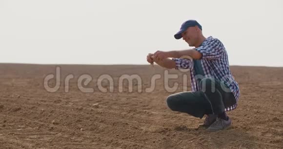 农民蹲在农场检查土壤质量视频的预览图